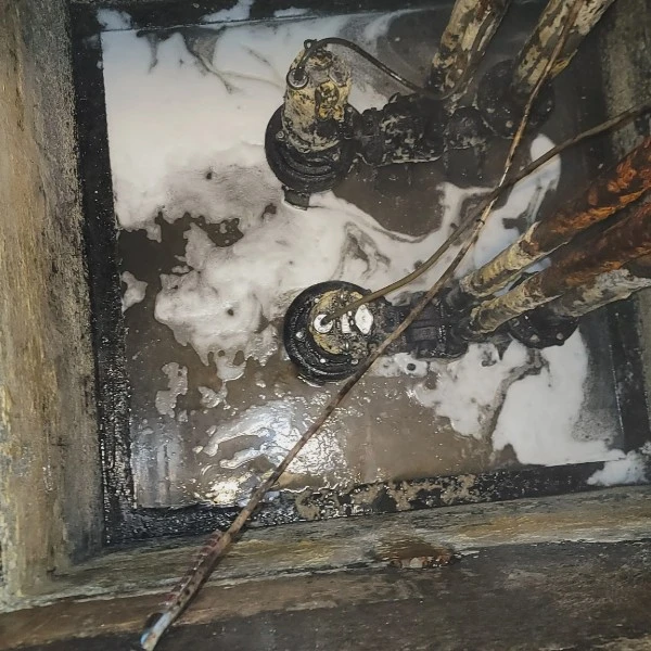 Cleaned sewer ejector pit with two submersible pumps and piping visible