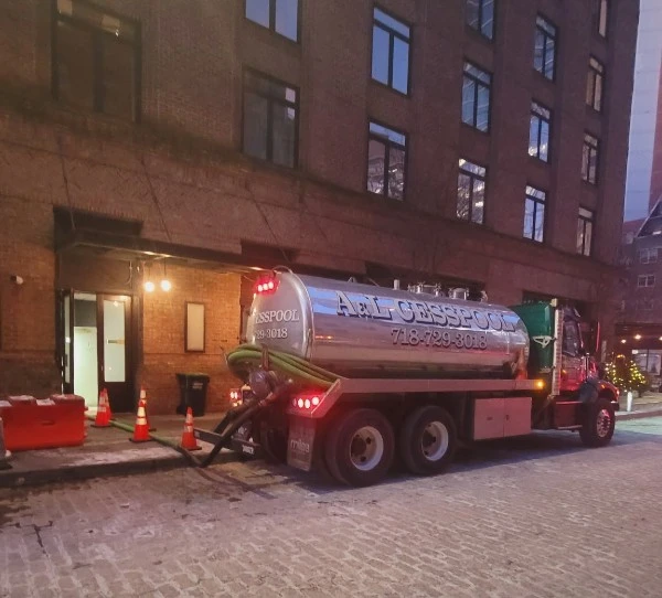 A&L Cesspool tanker truck pumping at night on a cobblestone Manhattan street