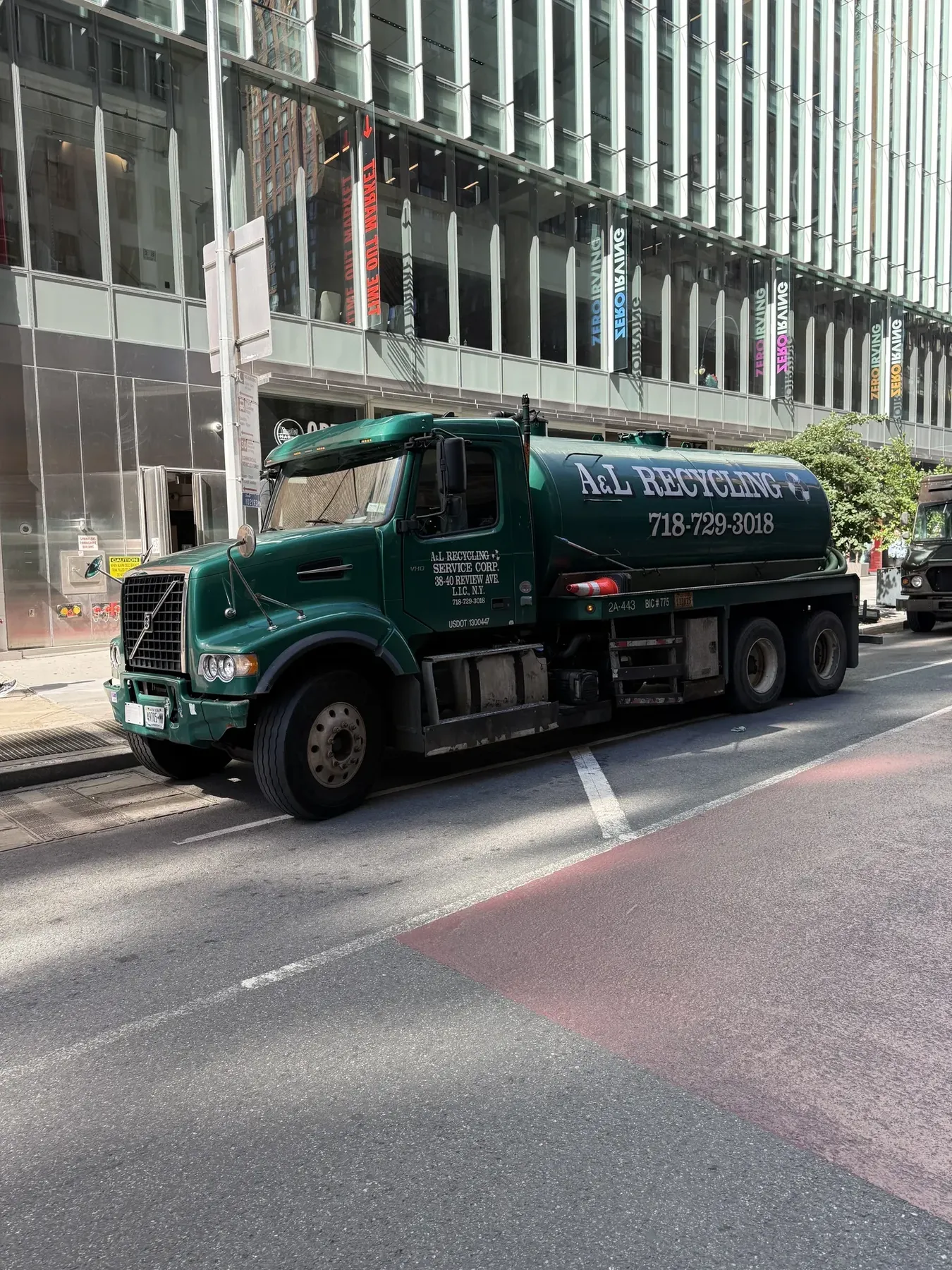 Green A&L Recycling tanker on a Manhattan street outside a glass office building