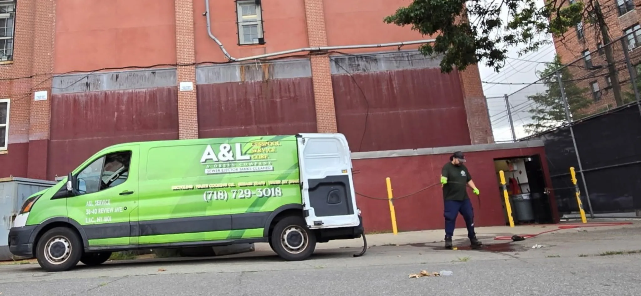 Bright green A&L jetting van with its rear doors open at a brick apartment building